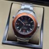 Omega — esfera negra, bisel naranja y brazalete de acero