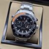 Omega — cronógrafo con esfera negra, bisel negro con detalle naranja y brazalete de acero