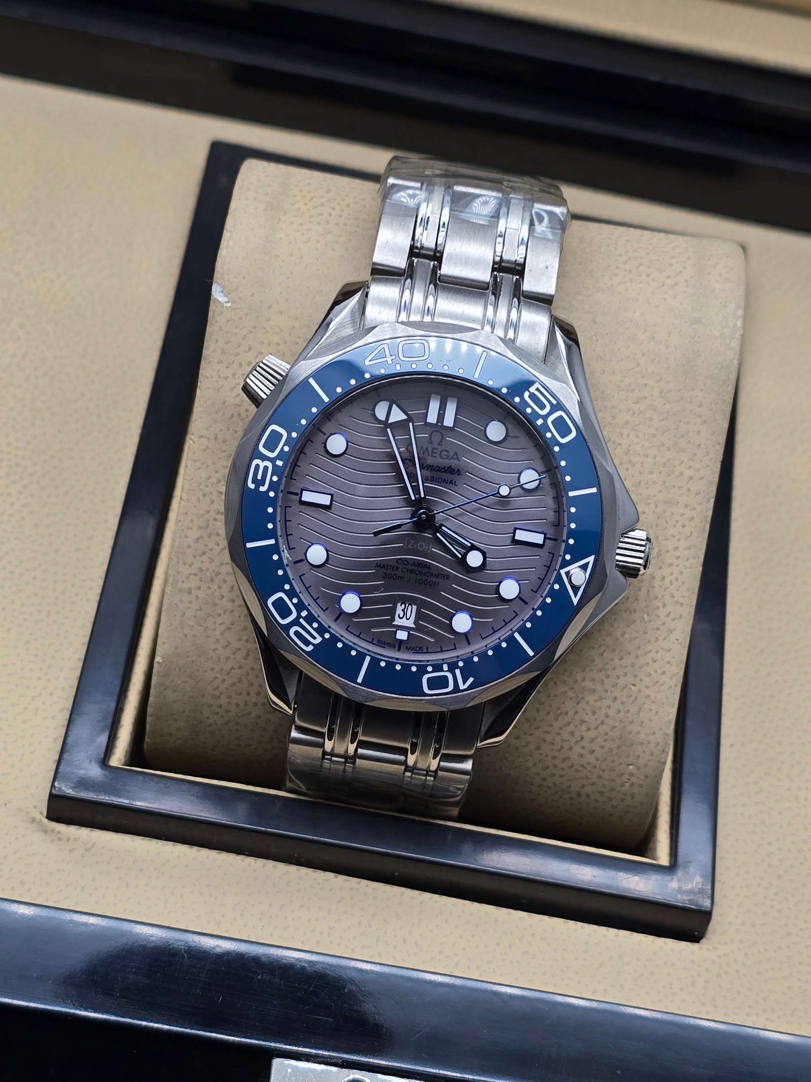 Omega — esfera gris ondulada, bisel azul y brazalete de acero