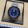 Omega — esfera azul con detalles naranjas y brazalete de malla de acero