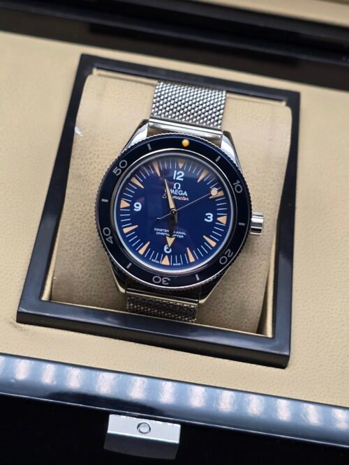 Omega — esfera azul con detalles naranjas y brazalete de malla de acero