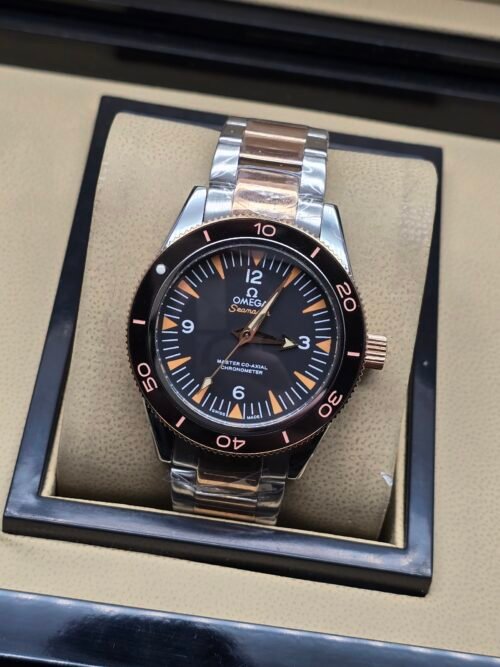 Omega — esfera negra con detalles naranjas, bisel oro rosa y brazalete bicolor