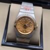 Omega — esfera dorada texturizada, bisel con brillantes y brazalete bicolor