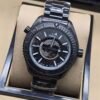 Omega — esfera negra con mapa gris, caja negra y brazalete negro