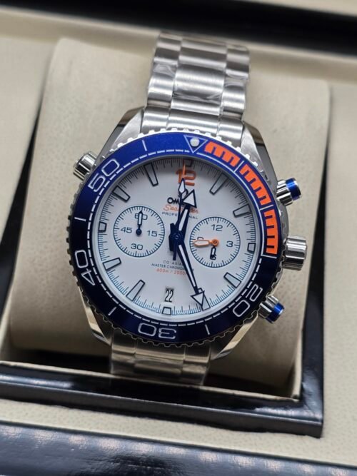 Omega — cronógrafo con esfera blanca, bisel azul con detalle naranja y brazalete de acero