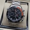 Omega — cronógrafo con esfera negra, bisel negro con detalle naranja y brazalete de acero