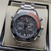 Omega — cronógrafo con esfera gris, bisel gris con detalle naranja y brazalete de acero