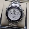 Omega — cronógrafo con esfera blanca ondulada, bisel negro y brazalete de acero