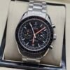 Omega — cronógrafo con esfera negra y detalles naranjas, brazalete de acero