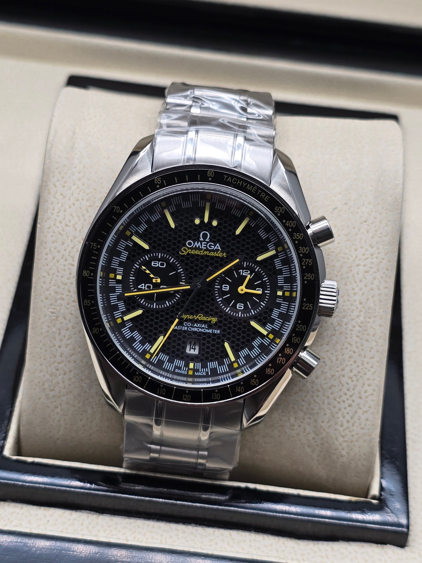 Omega — cronógrafo con esfera negra y detalles amarillos, brazalete de acero