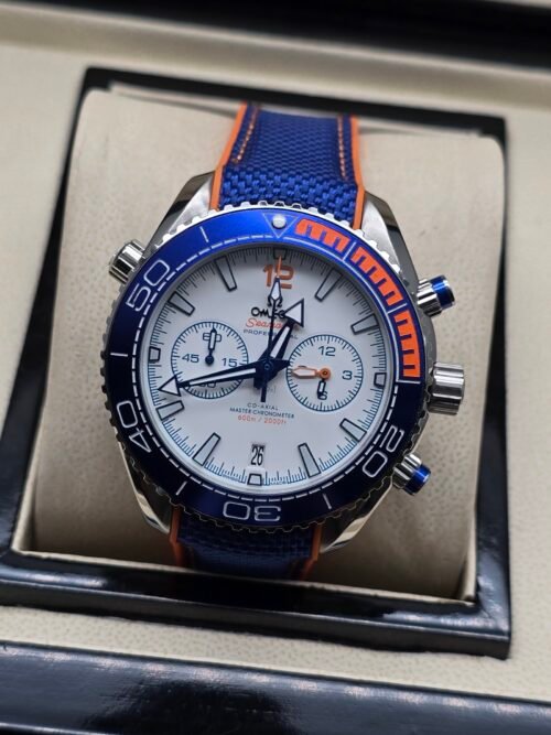 Omega — cronógrafo con esfera blanca, bisel azul con detalle naranja y correa de tela azul