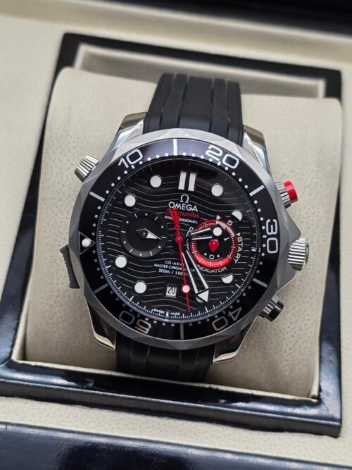 Omega — cronógrafo con esfera negra ondulada, detalles rojos y correa de caucho negra