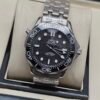 Omega — esfera negra texturizada, bisel negro y brazalete de acero
