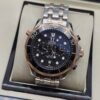 Omega — cronógrafo con esfera negra ondulada, bisel oro rosa y brazalete bicolor