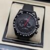 Omega — cronógrafo negro con aguja roja, caja negra y correa negra