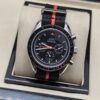 Omega — cronógrafo con esfera negra y detalles naranjas, correa de tela negra y naranja