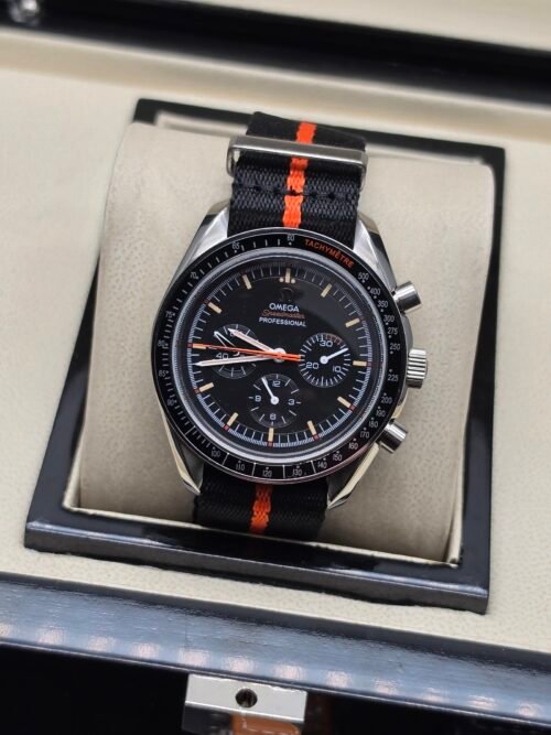 Omega — cronógrafo con esfera negra y detalles naranjas, correa de tela negra y naranja
