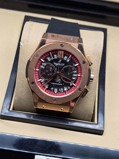 Hublot — cronógrafo con esfera negra y detalles rojos, caja oro rosa y correa negra