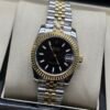 Rolex — esfera negra con índices, bisel dorado estriado y brazalete jubilee bicolor