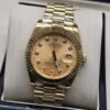 Rolex — esfera champaña con brillantes, bisel dorado estriado y brazalete dorado