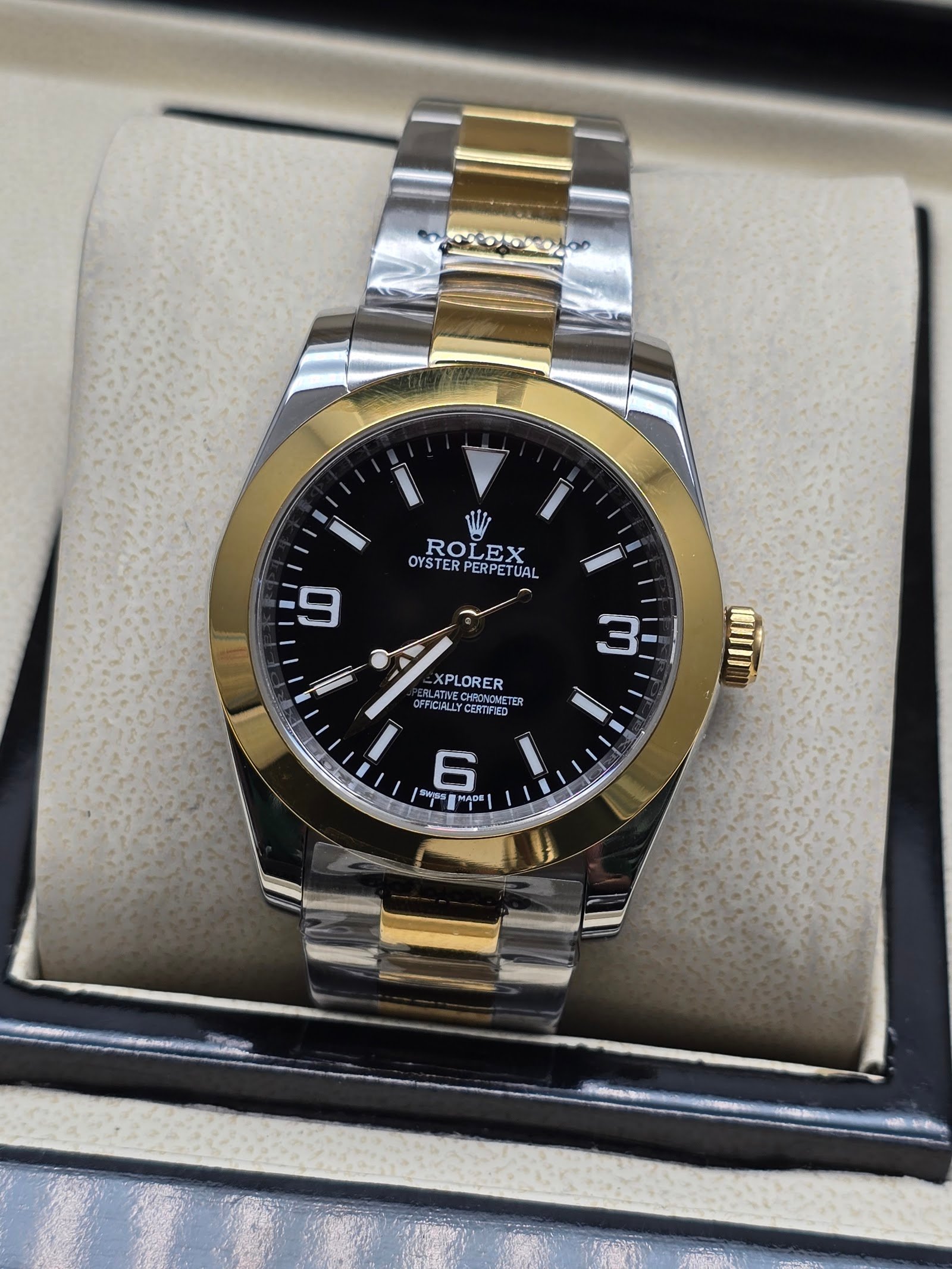 Rolex — esfera negra con números 3-6-9, bisel dorado y brazalete bicolor