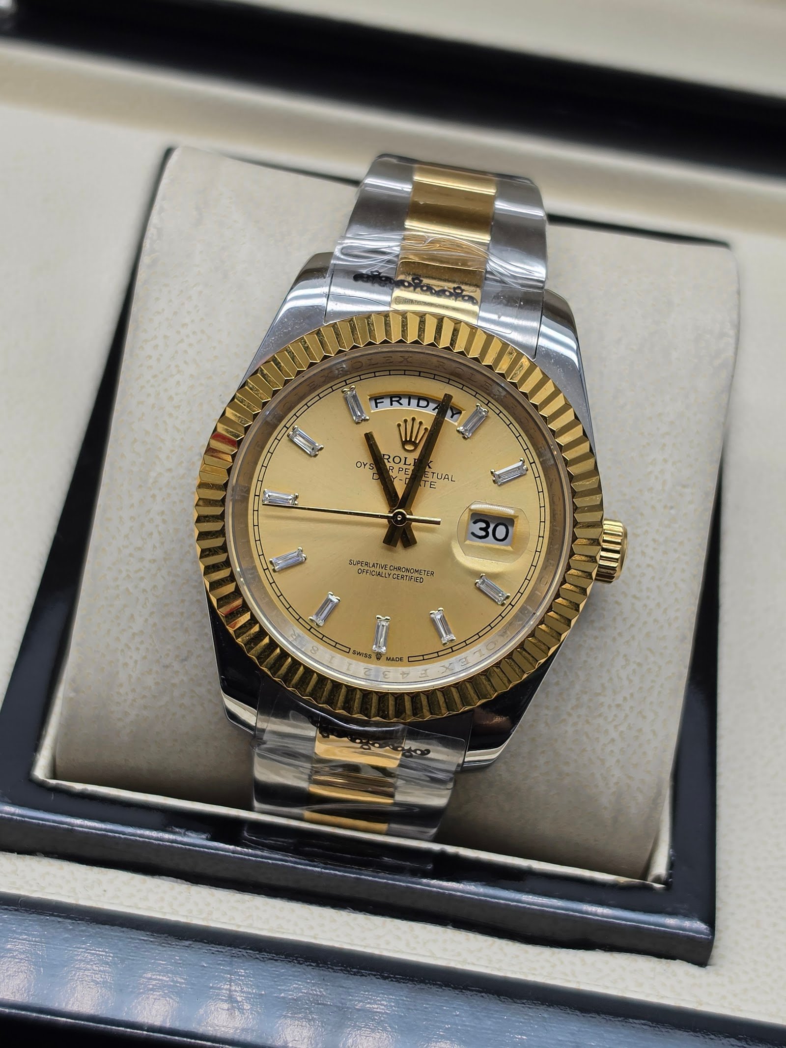 Rolex — esfera champaña con día y fecha, bisel dorado estriado y brazalete bicolor