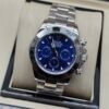 Rolex — cronógrafo con esfera azul, bisel negro y brazalete de acero