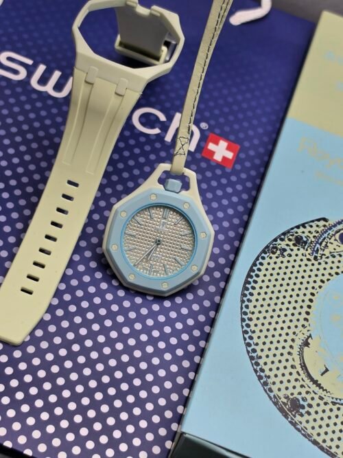 Swatch — reloj de bolsillo octagonal celeste con esfera clara y correa beige