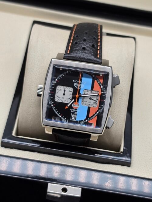 TAG Heuer — cronógrafo cuadrado con esfera negra y franjas celeste y naranja, correa de cuero negra