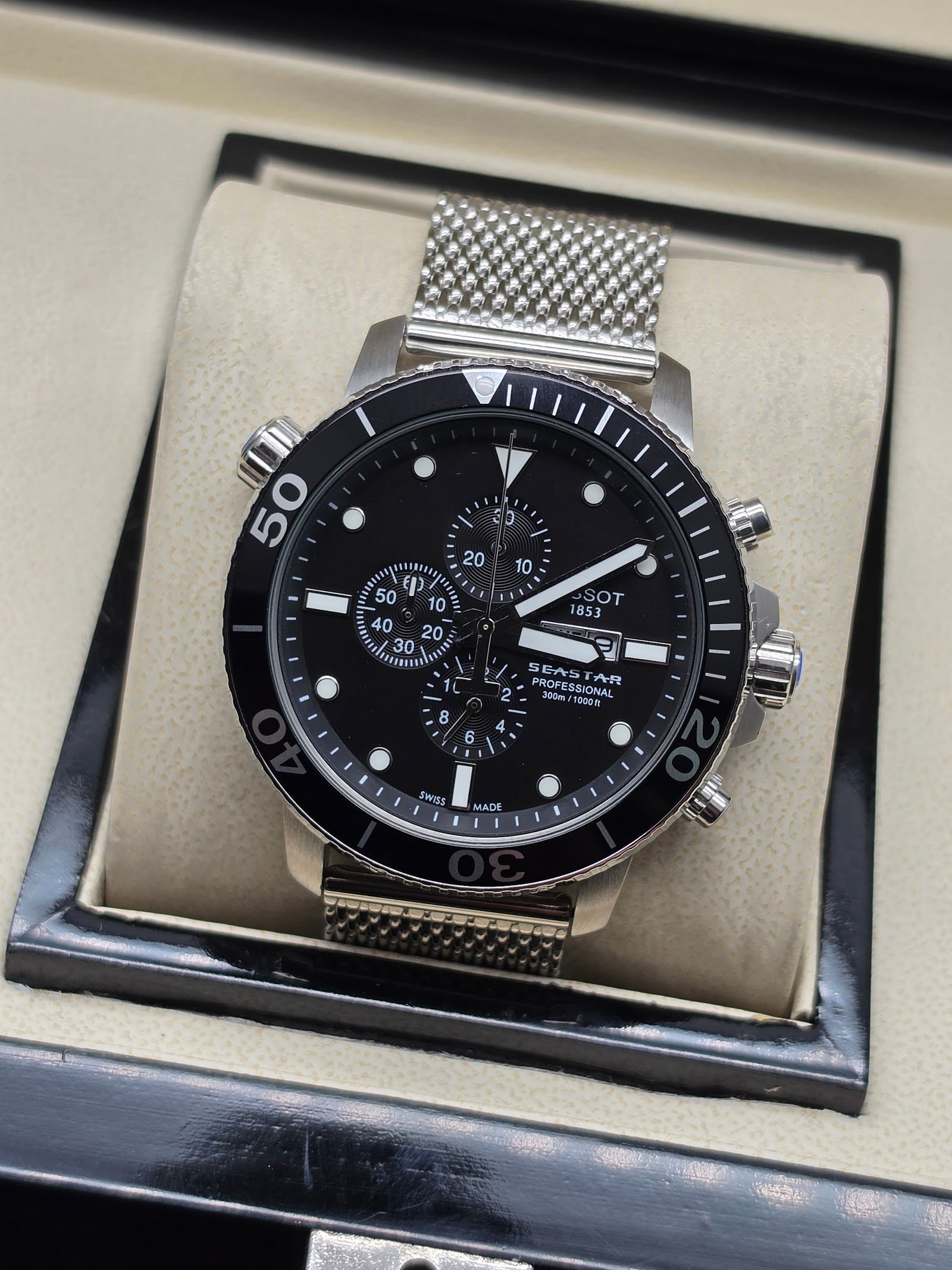 Tissot — cronógrafo con esfera negra, bisel negro y brazalete de malla de acero