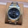 Rolex — esfera gris con números romanos verdes, bisel dorado estriado y brazalete bicolor