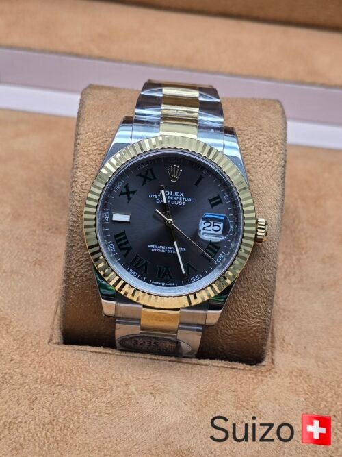 Rolex — esfera gris con números romanos verdes, bisel dorado estriado y brazalete bicolor