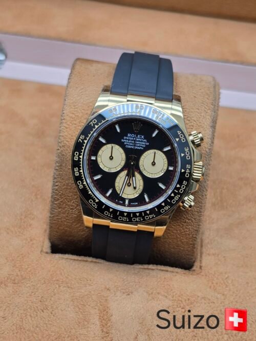 Rolex — cronógrafo con esfera negra y subesferas crema, caja dorada y correa de caucho negra