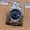 Rolex — esfera gris con números romanos, bisel estriado rosado y brazalete jubilee bicolor